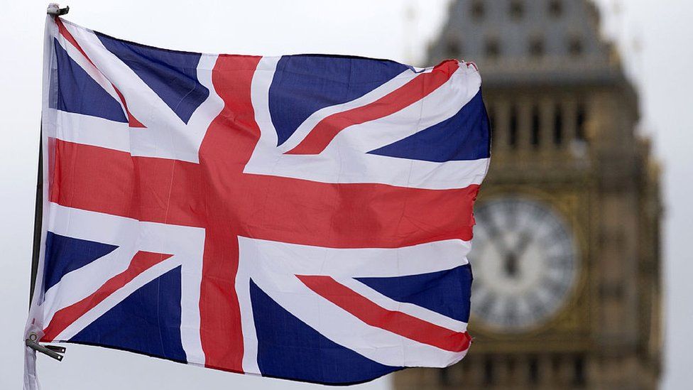 A union flag flies in front of the Palace of Westminster