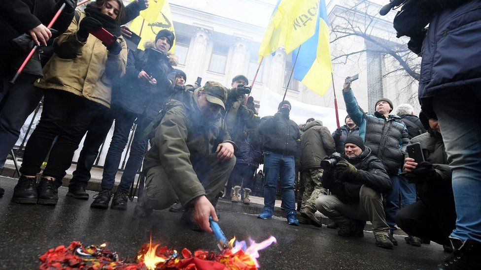 Activists burn the Russian flag and St George ribbons - symbols of the so called 'Russian world' - as they call for the deputies to recognise Russia as an aggressor state during a rally in front of the Ukrainian parliament in Kiev, on January 16, 2018