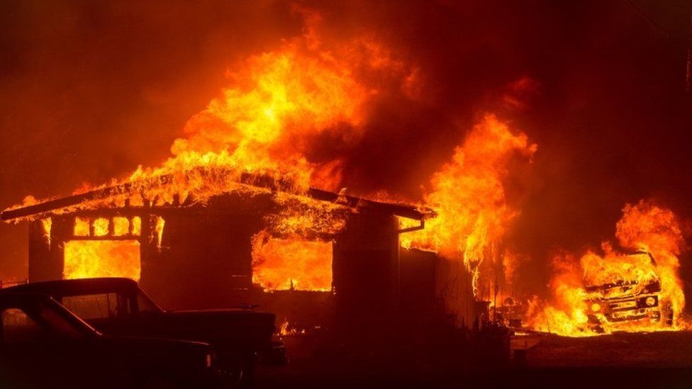 A car and house are engulfed in flames as the "Wall Fire" burns through a residential area in Oroville (09 July 2017)