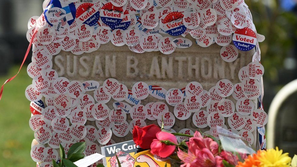 Susan B Anthony's grave is photographed littered with stickers