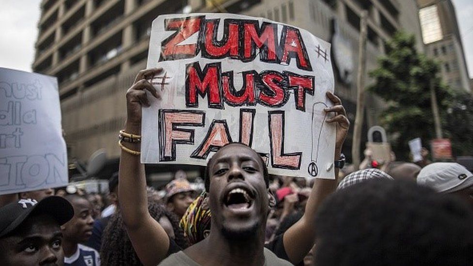 A student holds a placard reading 'A placard with 'Zuma must fall' outside the Luthuli House, the ANC headquarters, on October 22, 2015, in Johannesburg