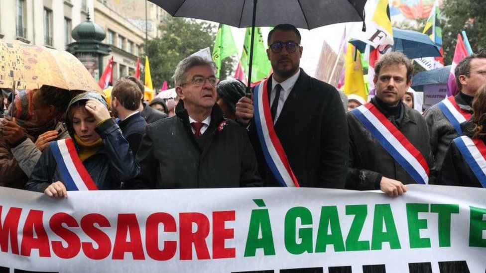 Jean-Luc Melenchon, member of French far-left opposition party La France Insoumise, stands in front of a banned and protesters at a demonstration demanding a ceasefire in Gaza. in Paris, on 4 November 2023.