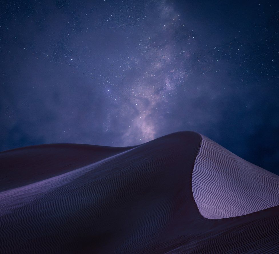 A view of sand dunes beneath a night sky