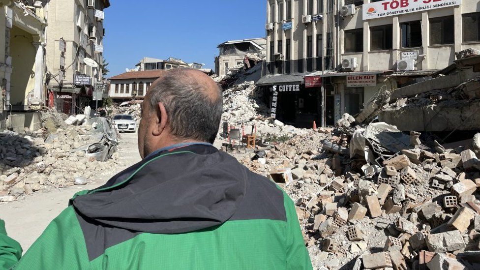 A man walks down a rubble-strewn street