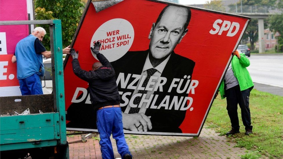 Workers remove an election campaign poster showing Social Democratic Party (SPD) leader and top candidate for chancellor Olaf Scholz, the day after the German general elections