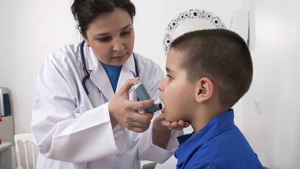 Child and health worker with asthma inhaler