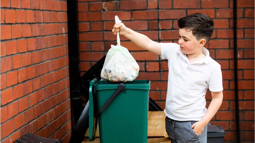 Boy puts food waste in recycling caddy