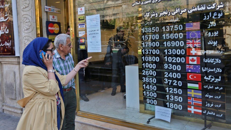 People walk past a foreign exchange shop in Tehran, Iran (22 April 2019)