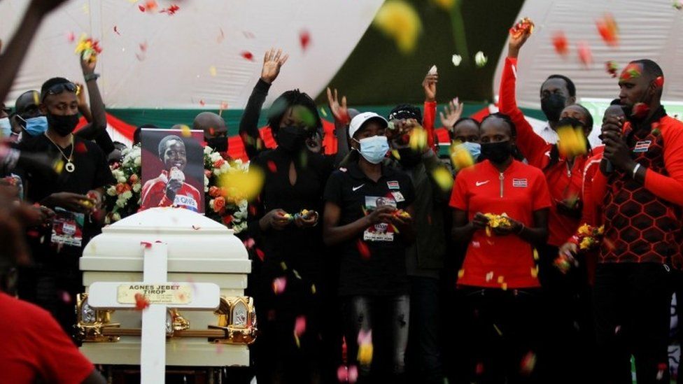 Kenyan athletes and mourners throw flowers at the coffin in memory of cross-country skier Agnes Tirop