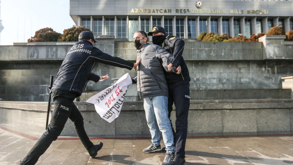 Police seize a poster saying "Journalism is not a crime" during a protest in Baku in 2021