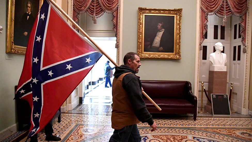 A protester holds a Confederate flag inside Congress