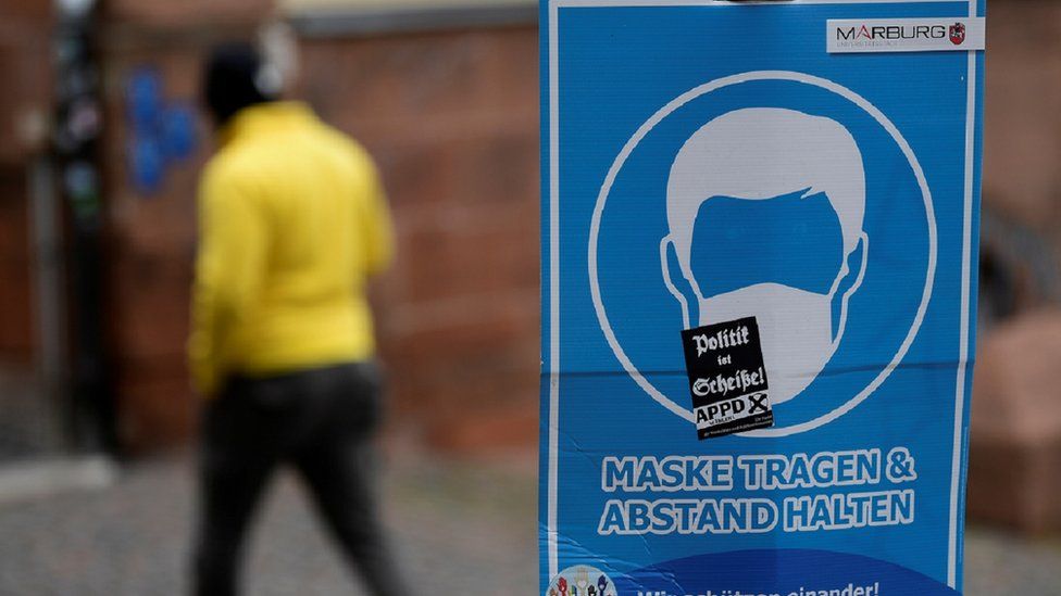 A man walking past a coronavirus sign in Germany