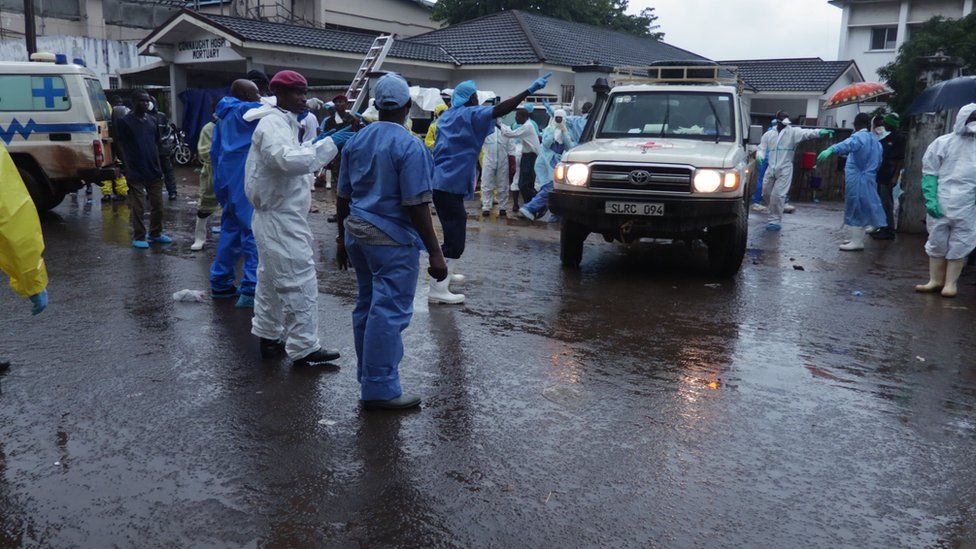 an ambulance pulls out of the mortuary with human remains that are being taken to a mass grave outside Freetown