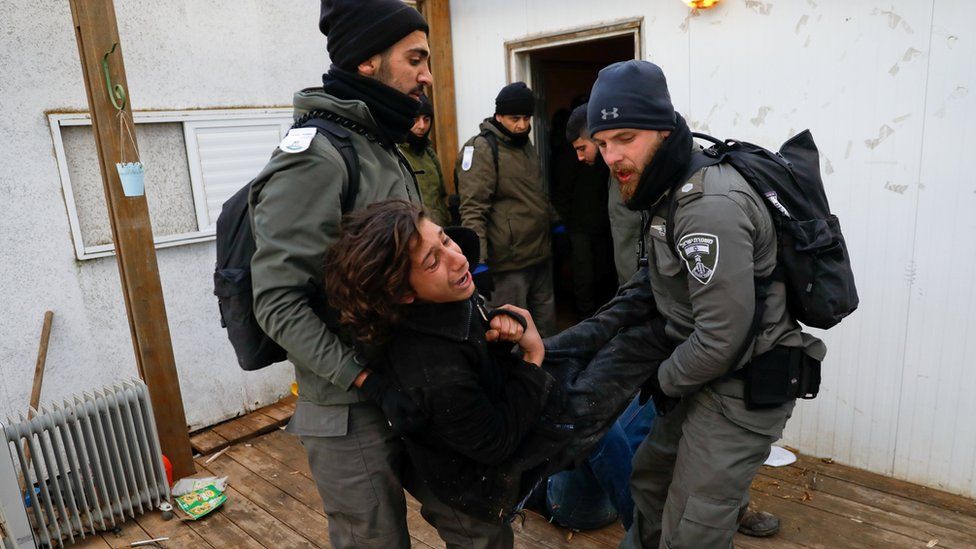 Israeli policemen remove a pro-settlement activist from a house during an operation to evict settlers from the unauthorised outpost of Amona in the occupied West Bank (1 February 2017)