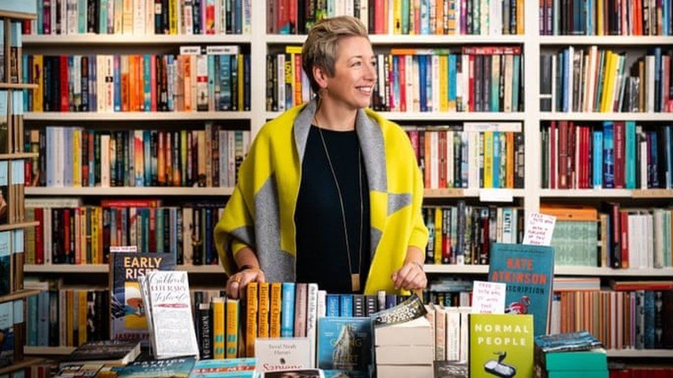 Emma Corfield-Walters standing in from of shelves full of books