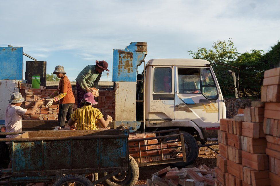 Workers load bricks on a truck in a kiln located in Kandal province.