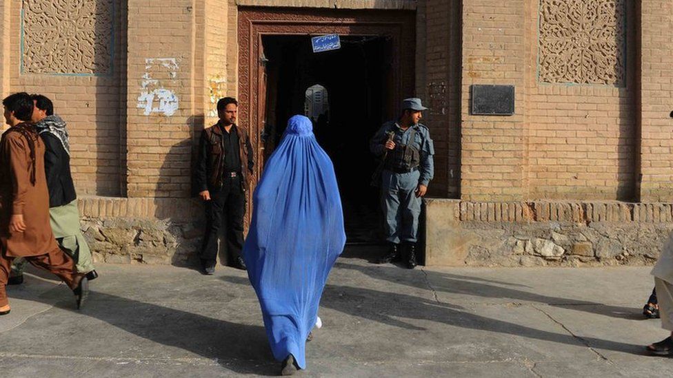A woman walks into a building in Herat