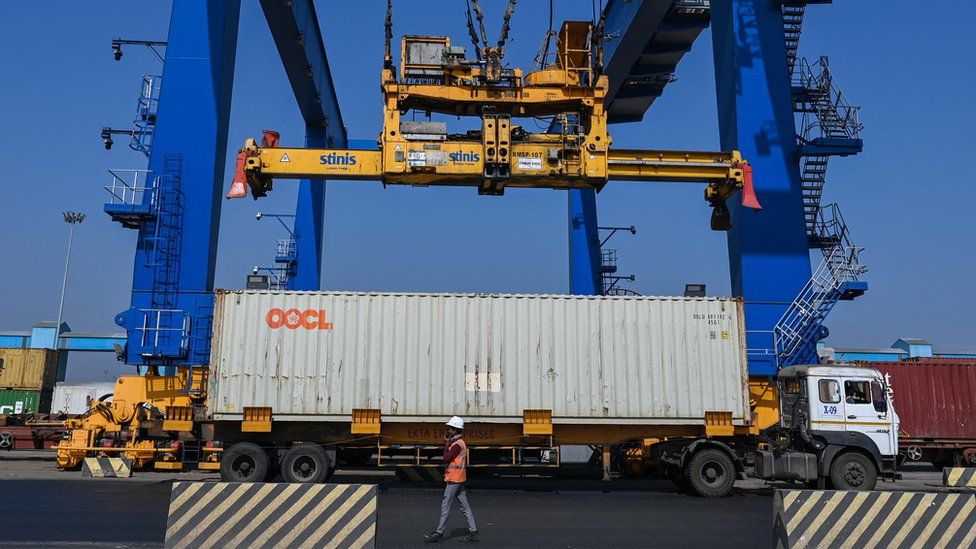 A crane loads a cargo container on a truck inside the Mundra Port, India.