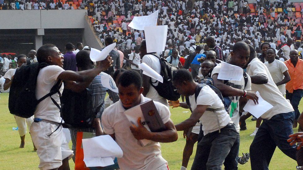 Job-seekers appling for work at the Nigerian immigration department scramble as their exam papers fly in the air, on the pitch of Abuja National Stadium, on March 15, 2014.
