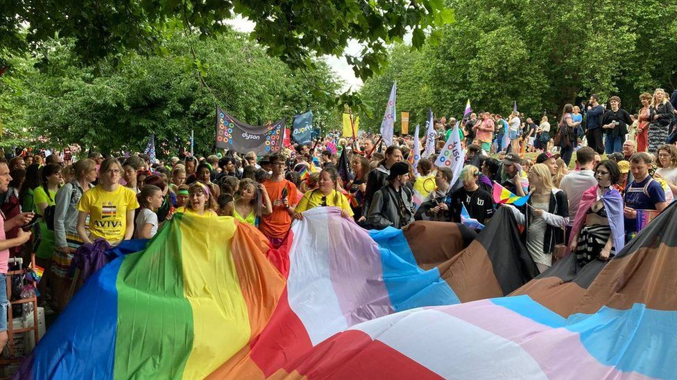 Pride crowd holding a giant Pride flag