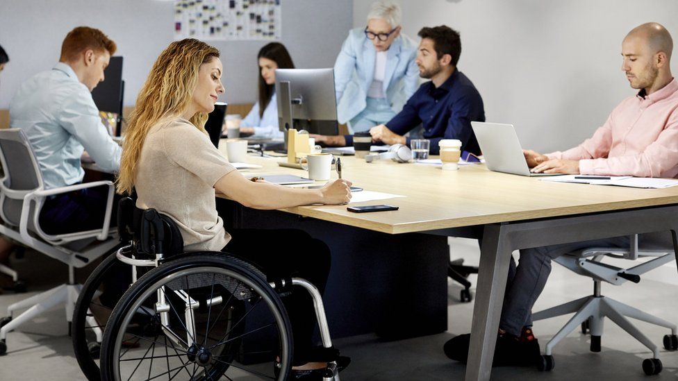 Wheelchair using young woman takes notes in a meeting
