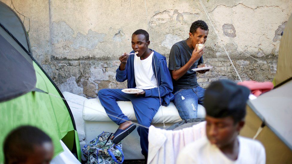 Migrants are fed by an NGO at a makeshift camp in Rome