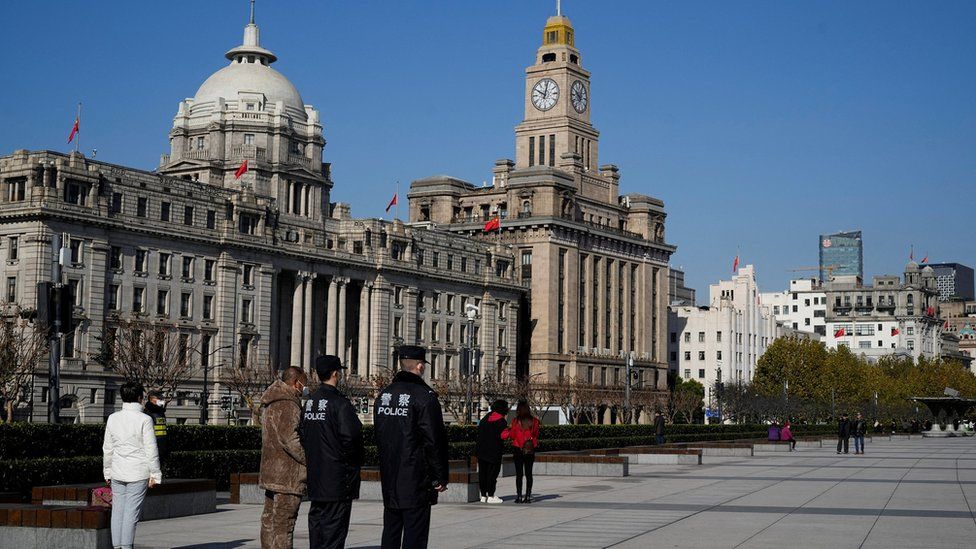 Pedestrians and police guards stand to attention for a three-minute silence in Shanghai