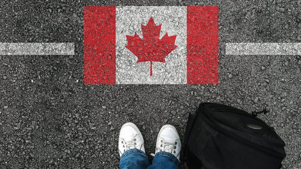 Person in front of a picture of a Canadian flag
