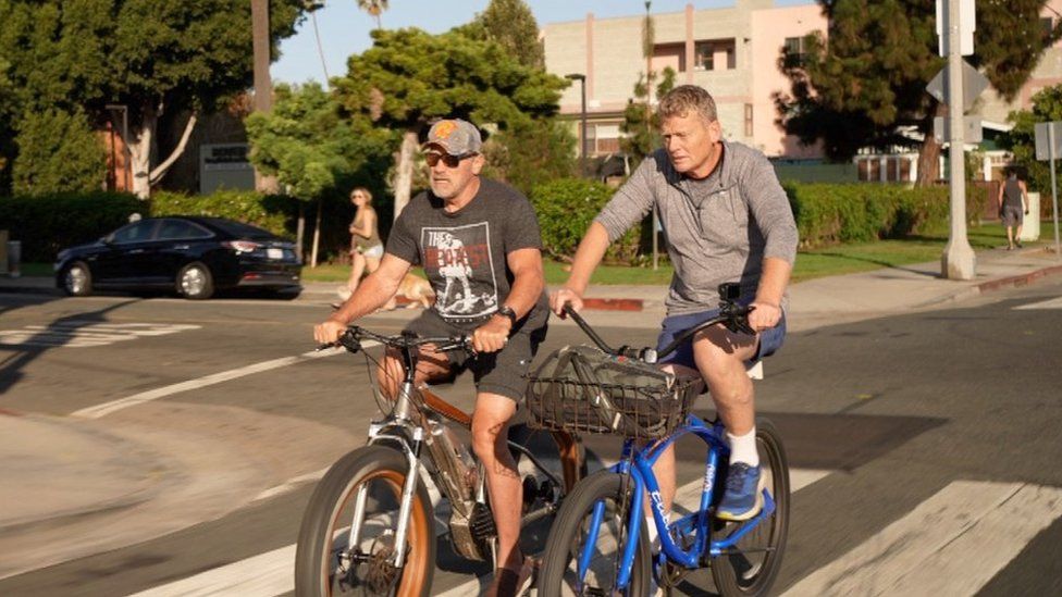 Arnold Schwarzenegger (left) and Tom Heap riding bikes