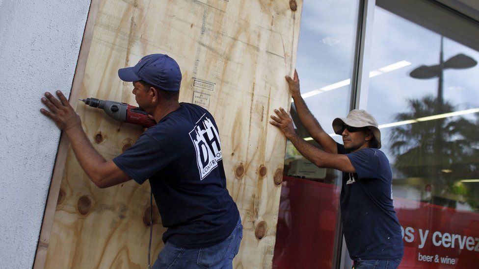 People board up windows of a business in preparation for the anticipated arrival of Hurricane Maria in San Juan, Puerto Rico on September 18, 2017
