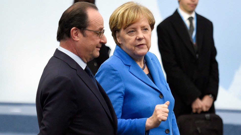 French president Francois Hollande, left, and German Chancellor Angela Merkel arrive for a group photo during the COP21, United Nations Climate Change Conference, in Le Bourget, outside Paris, Monday, Nov. 30, 2015
