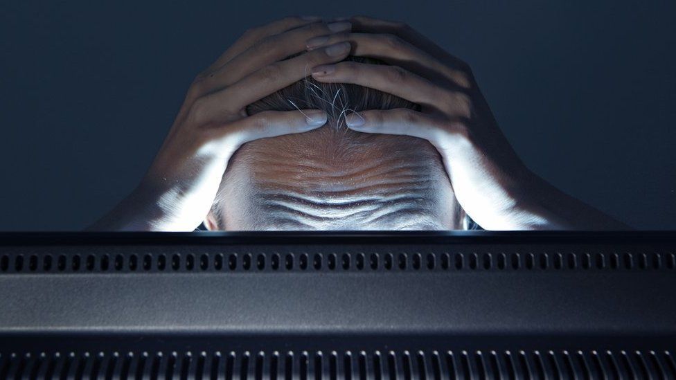 A stock image of a person staring in frustration at a computer monitor