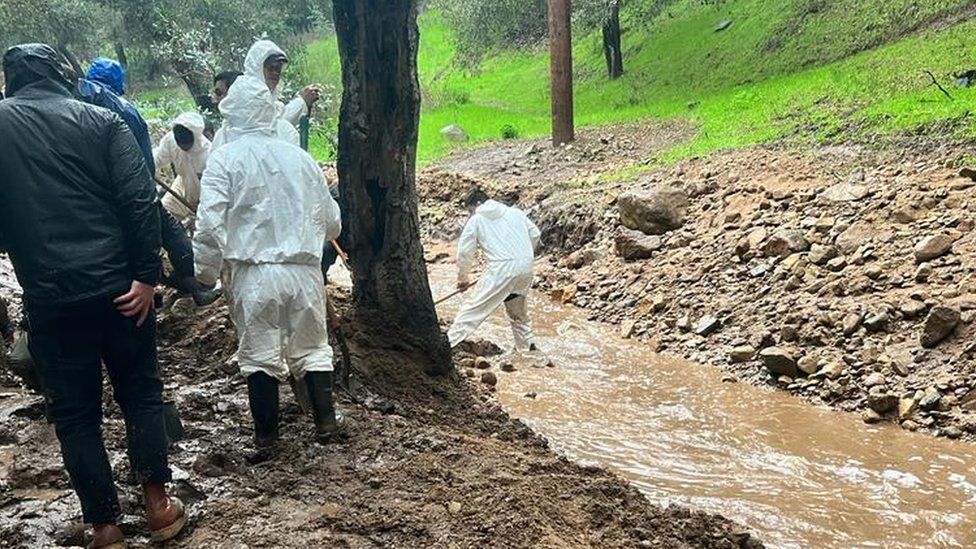 Volunteers digging trenches after giant boulders and mud blocked access to some homes in California