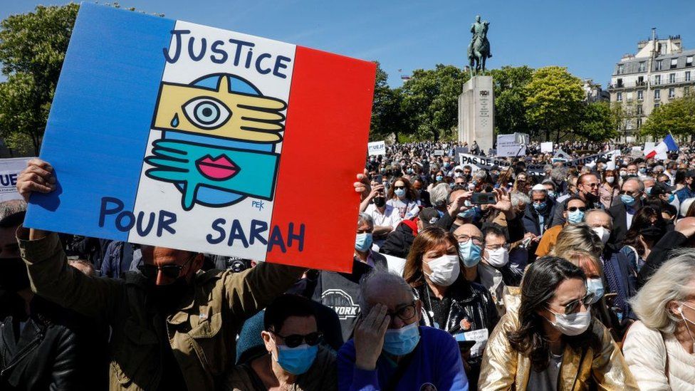 Мужчина держит плакат с надписью «Справедливость для Сары», когда люди собираются, чтобы просить правосудия над покойной Сарой Халими на площади Трокадеро в Париже 25 апреля 2021 г.