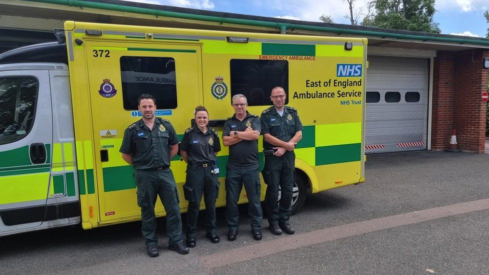 Four staff in front of an ambulance