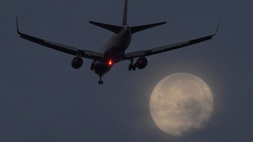 Plane lands in front of supermoon