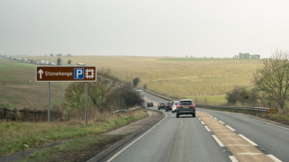 A303 at Stonehenge with cars passing the stones which are seen in the distance