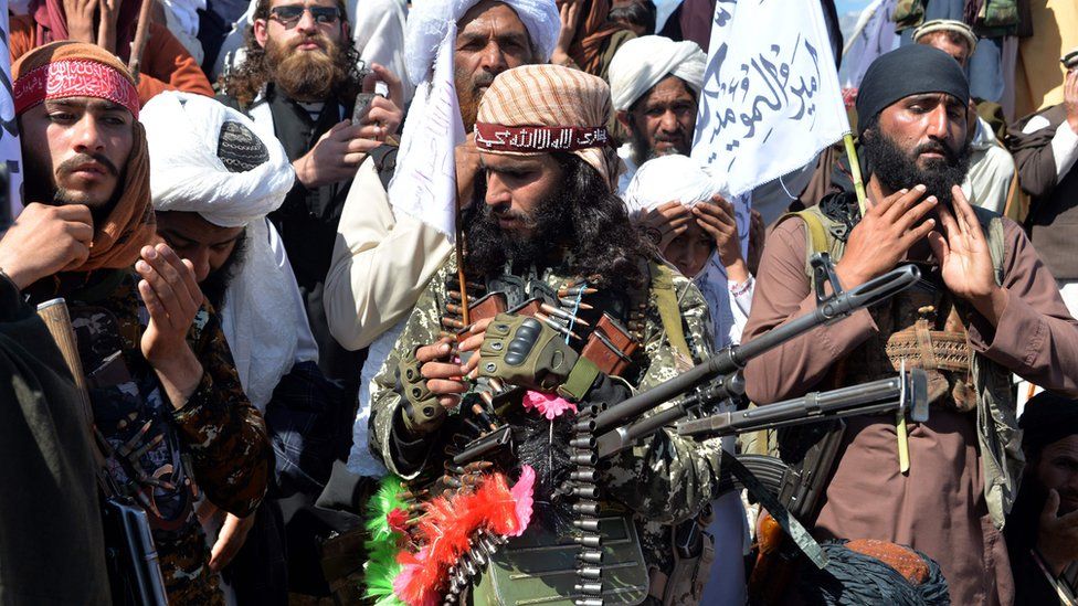 Afghan Taliban militants and villagers attend a gathering