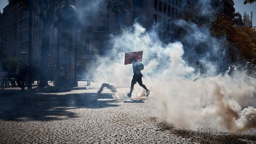 Activists run through clouds of tear gas