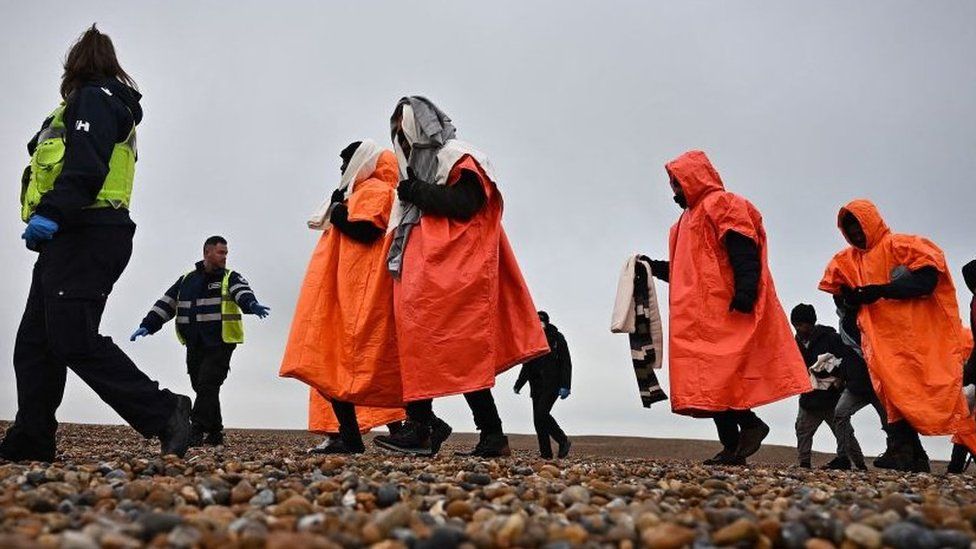 A British Immigration Enforcement officer and an Interforce security officer escort migrants, picked up at sea by a lifeboat whilst they were attempting to cross the English Channel