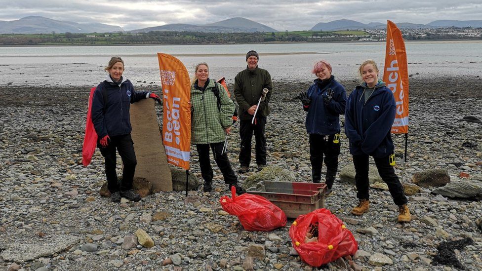 Beach clean-up volunteers with bags of rubbish