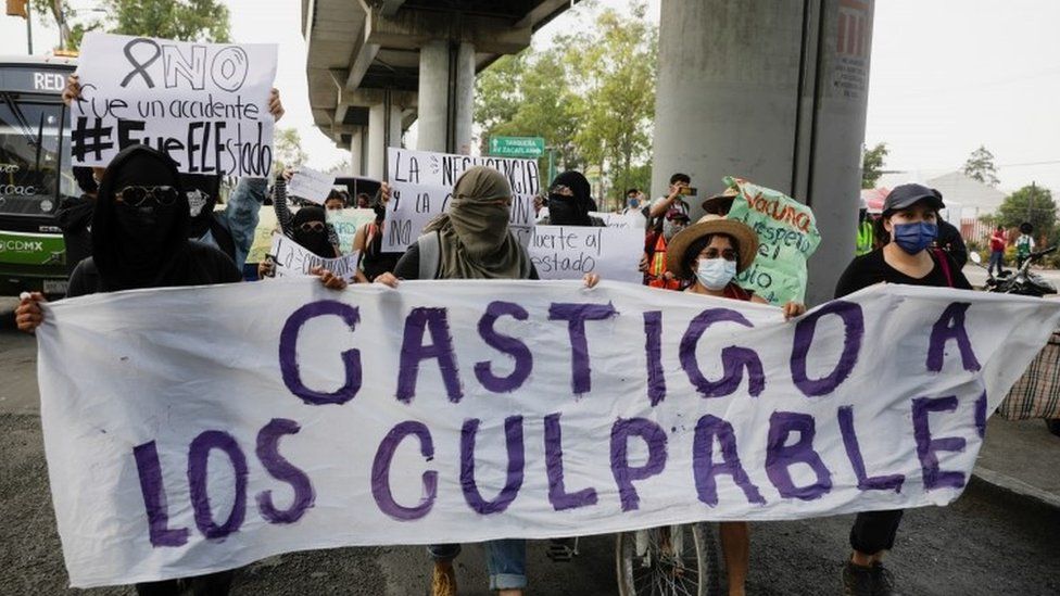 People hold a banner during a march to protest against the government after an overpass of the metro partially collapsed with train cars on it in Mexico City