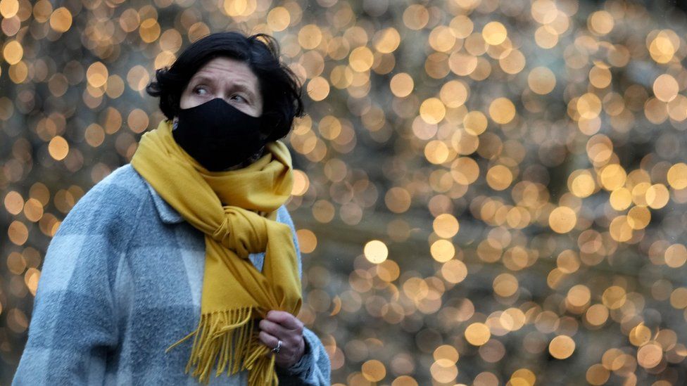 A woman wears a Covid-19 face mask as she walks past Christmas lights on December 08, 2021 in Manchester, United Kingdom