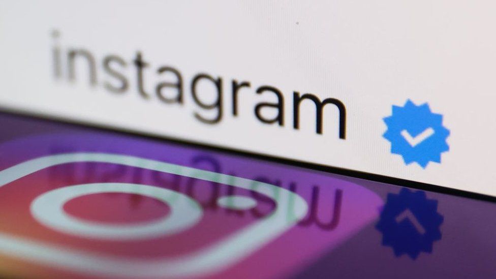 Instagram logo displayed connected  a smartphone with a bluish  verification badge