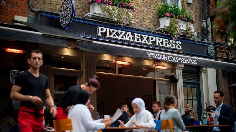 Customers sit outside Pizza Express restaurant in Central London