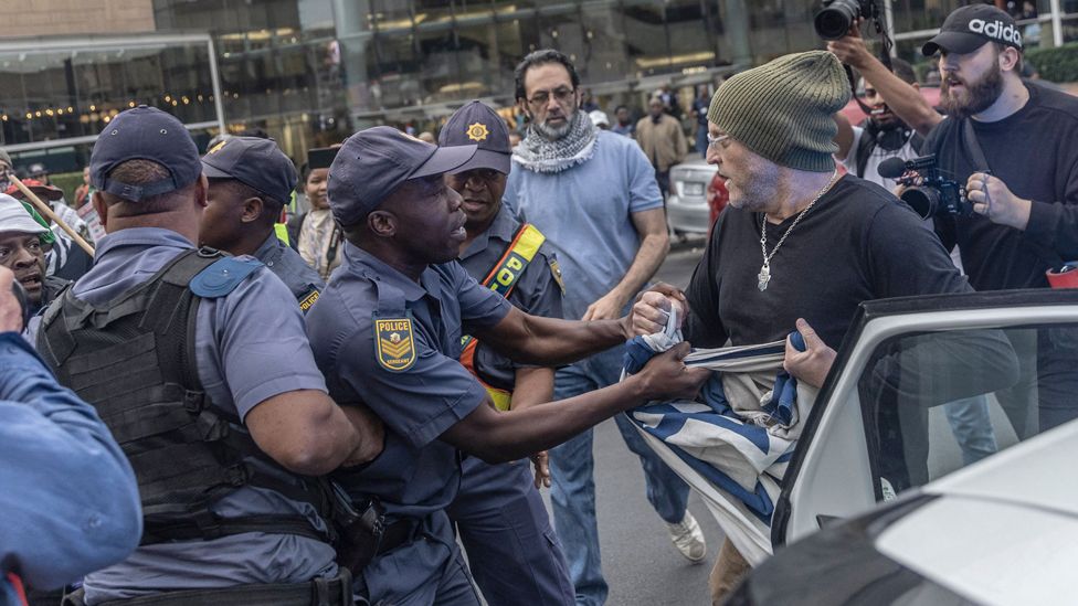 A police officer tries to remove an Israeli flag from a man in Sandton, Johannesburg, South Africa - Wednesday 11 October 2023