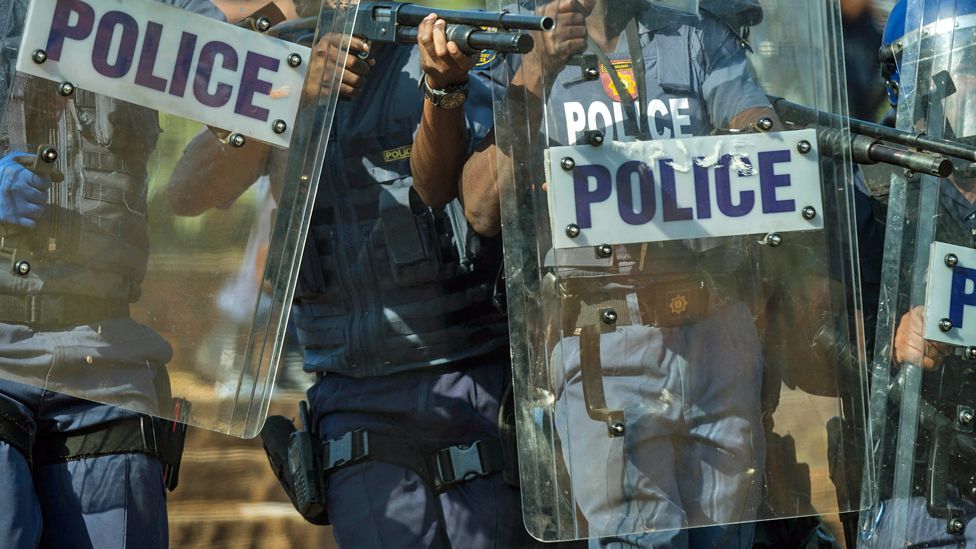 Police with shields and one pointing a gun during a protest in Pretoria, South Africa - archive shot