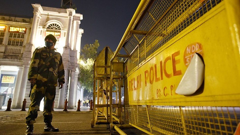 Сотрудники службы безопасности устанавливают и охраняют баррикады, чтобы обеспечить соблюдение ограничений в канун Нового года на Коннот-плейс 31 декабря 2021 года в Нью-Дели, Индия.