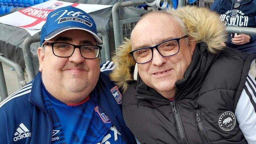 Steve Kirby and Gary Battle standing in the Sir Bobby Robson stand ahead of an Ipswich Town game. Both wearing Ipswich Town clothing