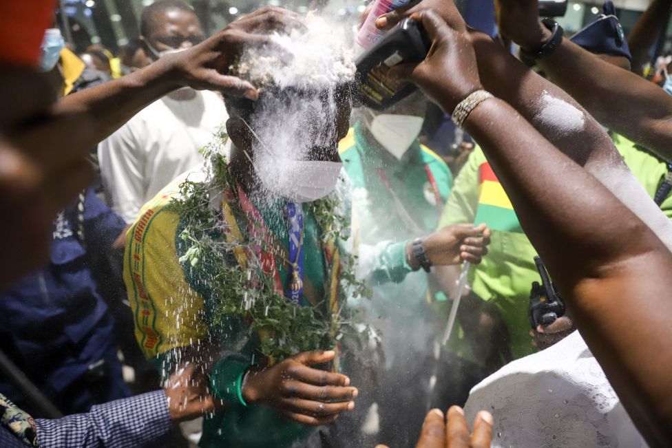 Ghanaian boxer Samuel Takyi has powder sprinkled over him - a sign of victory - as he is greeted by supporters in the arrival hall of The Kotoka International Airport in Accra late August 13, 2021,